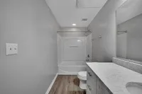 Elegant bathroom with modern fixtures, showcasing a pristine bathtub, sleek marble countertop, and stylish gray walls.