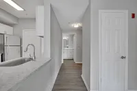 Sleek modern kitchen with stylish countertops and stainless steel appliances leading to a bright hallway.
