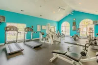 Bright and airy fitness center with modern equipment, featuring treadmills, weight machines, and vibrant turquoise walls.