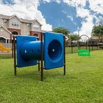 Charming apartment complex with a vibrant outdoor play area and clear blue skies, perfect for family-friendly living.