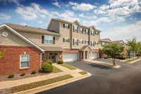 Charming townhouse complex with three stories, red brick facade, and garages, set against a bright, blue sky.