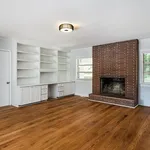 Charming living room with a rustic brick fireplace, elegant built-in shelves, and warm wooden floors.
