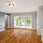 Bright and inviting living room with elegant hardwood flooring, large windows, and modern light fixture.