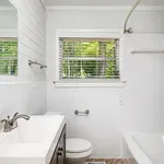 Bright and inviting bathroom with modern fixtures, a large window offering lush greenery views, and elegant white tiles.