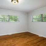 Bright and airy room with hardwood floors, natural light from dual windows, and a modern light fixture.