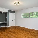 Bright and airy room with polished wooden floors, sleek modern lighting, and large windows offering a serene green view.