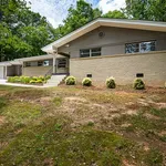 Charming single-story home with modern architecture, featuring a well-maintained front yard and surrounded by lush greenery for serene living.