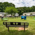 Charming community park with playful paw-print bench, vibrant green spaces, and engaging play equipment, surrounded by cozy residential homes.