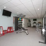 Modern fitness area with state-of-the-art equipment, featuring treadmills, weights, and aerobic steps in a sleek, well-lit space.