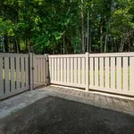 Charming patio with elegant beige fencing overlooking lush greenery, perfect for outdoor relaxation.