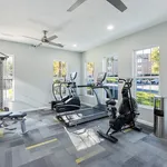 Bright and modern fitness room with sleek equipment and large windows overlooking green spaces.