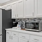 Elegant kitchen with sleek white cabinets, modern appliances, and a stylish coffee bar on a polished countertop.
