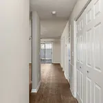 Inviting apartment hallway with elegant wood flooring and ample natural light from glass doors.