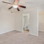 Bright bedroom with plush carpet, ceiling fan, and direct access to a modern en-suite bathroom and spacious closet.