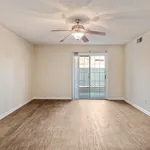 Bright empty room with elegant wood flooring, ceiling fan, and sliding glass doors leading to a serene patio space.