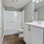 Modern bathroom with elegant cabinetry, sleek fixtures, and a pristine bathtub complemented by stylish wood flooring.