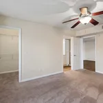 Inviting bedroom with plush carpet, ceiling fan, and a walk-in closet, perfect for a cozy and comfortable living space.