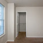 Inviting room with plush carpet flooring and a spacious walk-in closet, accented by natural light from a large window.