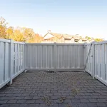 Charming outdoor patio with white privacy fence and rustic brick flooring, perfect for relaxing under a clear blue sky.