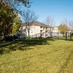 Charming apartment building surrounded by lush green lawn and scenic trees under a clear blue sky.