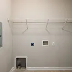Spacious laundry room with convenient shelving and utility connections, ready for appliance installation.