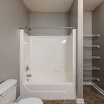 Modern apartment bathroom featuring a sleek white bathtub, elegant gray walls, and convenient built-in shelving, perfect for contemporary living.