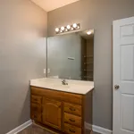 Modern bathroom with elegant wooden vanity, large mirror, and soft, warm lighting.