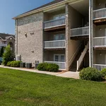Charming apartment building with balconies and lush green landscaping, offering a welcoming and serene living environment.