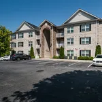 Charming brick apartment complex with modern architecture, featuring well-maintained greenery and ample parking space.
