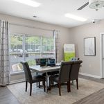 Bright office space with large windows, modern decor, and elegant gray seating arranged around a polished table, perfect for productive meetings.
