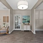 Inviting hallway featuring elegant hardwood floors, modern decor, and a chic glass door leading to spacious living areas.