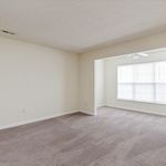 Bright and airy living space with plush carpeting, large windows, and modern ceiling fan, perfect for comfortable living.