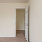 Spacious walk-in closet entry in a modern apartment with plush carpet flooring and neutral walls.