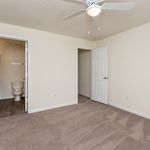 Bright and inviting bedroom with plush carpet, featuring an elegant ceiling fan and a convenient ensuite bathroom.