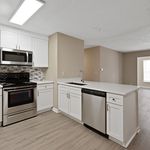 Modern kitchen with sleek stainless steel appliances, elegant white cabinetry, and a stylish backsplash, flowing into a bright open living area.