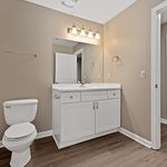 Modern bathroom with sleek white vanity, elegant lighting fixtures, and warm neutral tones. Perfect space for relaxation and refreshment.