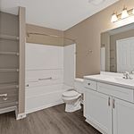 Elegant bathroom with modern fixtures, featuring a sleek vanity, spacious bathtub, and stylish wood-tone flooring.