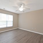 Bright and airy room with elegant gray flooring and large window, enhanced by a ceiling fan for modern comfort.
