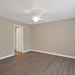 Bright and spacious bedroom with elegant wood flooring, featuring a modern ceiling fan and a doorway leading to an adjacent room.