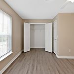 Bright bedroom with elegant wooden floors, large window for natural light, and spacious closet with double doors.