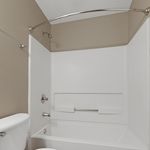 Elegant bathroom featuring a modern bathtub with a curved shower rod, sleek fixtures, and neutral color palette.