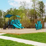 Inviting playground with vibrant blue slides and climbing structure surrounded by lush greenery, perfect for family enjoyment.