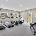 Modern fitness room with state-of-the-art treadmills, exercise bikes, and a weight bench, offering a bright and inviting workout space.
