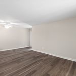Spacious room with elegant dark wood flooring and soft neutral walls, enhanced by a ceiling fan for comfort.