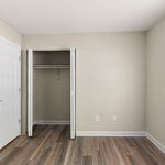 Spacious empty room with elegant laminate flooring and an open closet, perfect for personalization and storage.