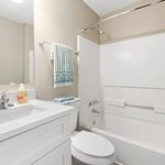 Bright and modern bathroom featuring a sleek white vanity, stylish fixtures, and a cozy bathtub with chic decor.