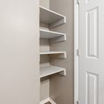 Compact corner shelving unit with sleek white shelves, perfect for maximizing storage and adding modern elegance to any room.