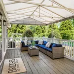 Charming covered patio with elegant wicker seating, ideal for relaxing and enjoying a lush garden view.