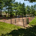 Charming dog park surrounded by lush greenery and tall trees, ideal for pets to play and explore.