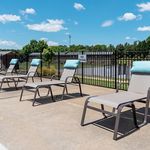 Inviting poolside area with comfortable lounge chairs and scenic views, perfect for relaxing under the sunny blue sky.